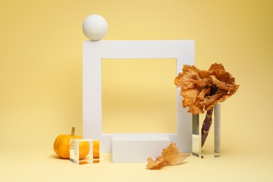 Photo of Autumn presentation for product. Geometric figures, pumpkin and dry leaves on beige background