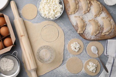 Process of making dumplings (varenyky) with cottage cheese. Raw dough and ingredients on grey table, flat lay