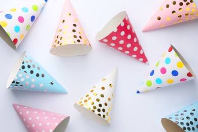 Colorful party hats on light background, top view