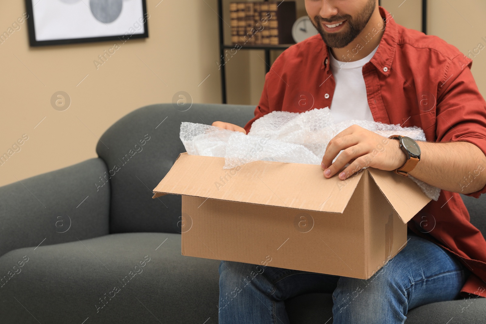 Photo of Man unpacking parcel at home, closeup. Online shopping