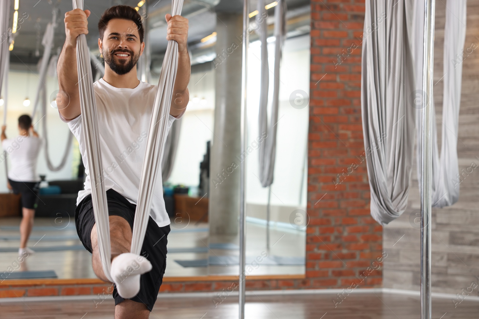 Photo of Man with hammock practicing fly yoga in studio