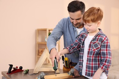Photo of Father and son screwing wooden plank at home. Repair work