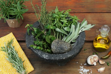 Mortar, different herbs, vegetables and oil on wooden table