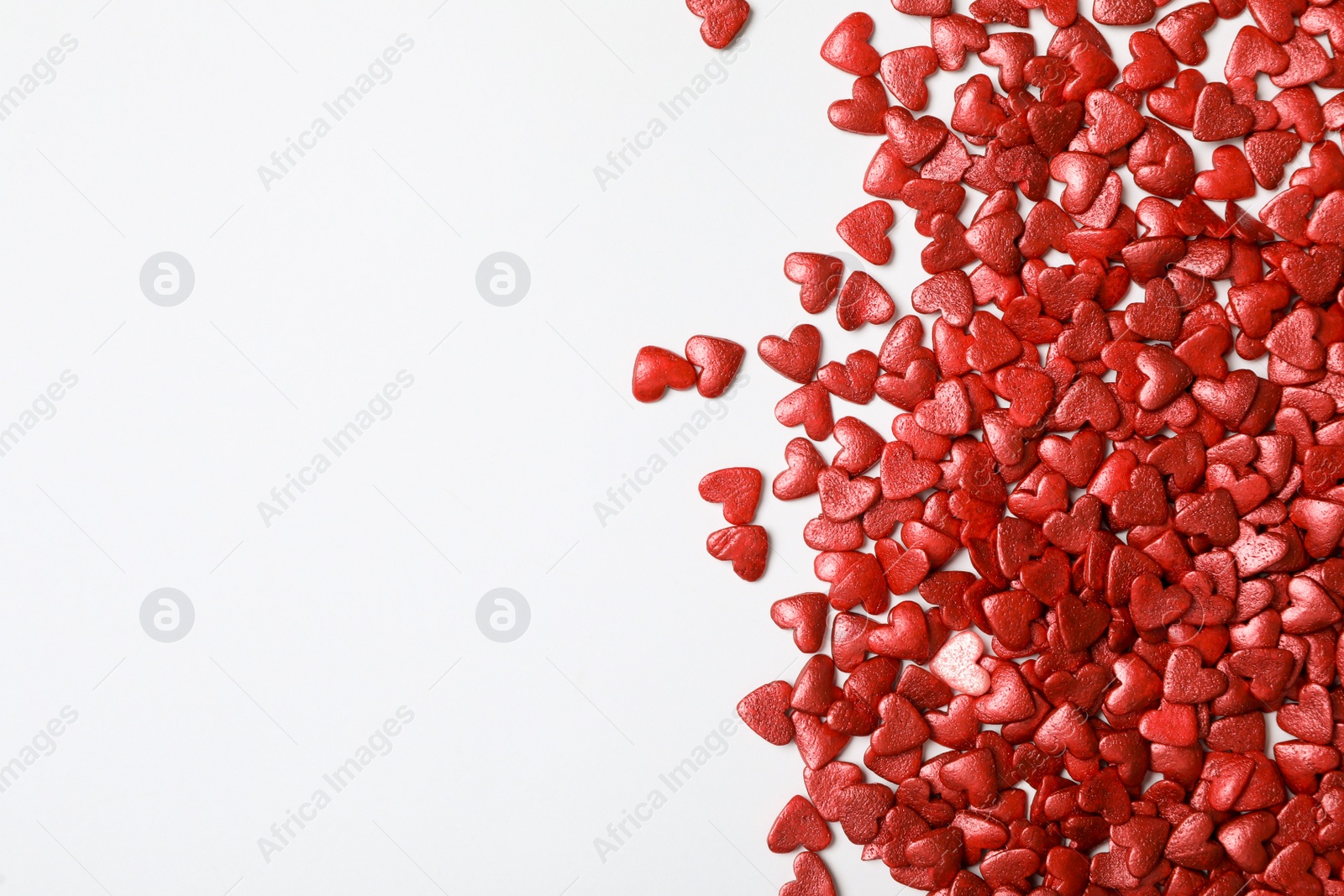 Photo of Bright heart shaped sprinkles on white background, flat lay. Space for text
