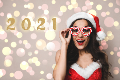 Image of Emotional young woman in Christmas costume with party glasses on beige background. Bokeh effect