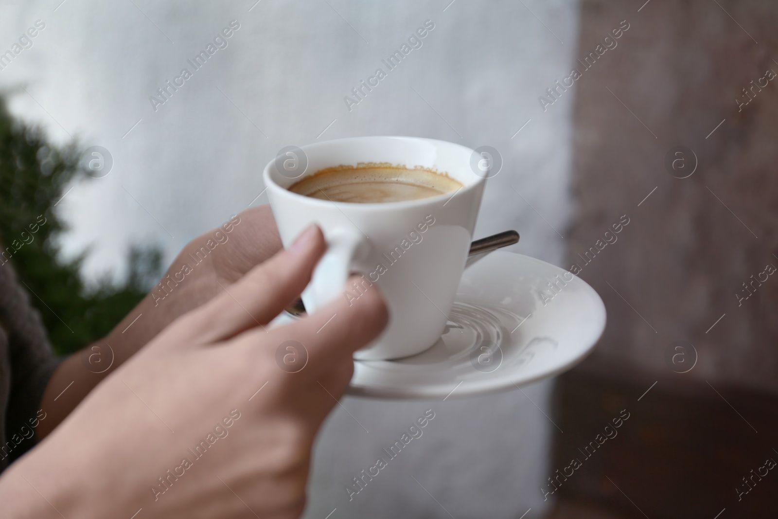 Photo of Young woman with cup of delicious coffee on blurred background