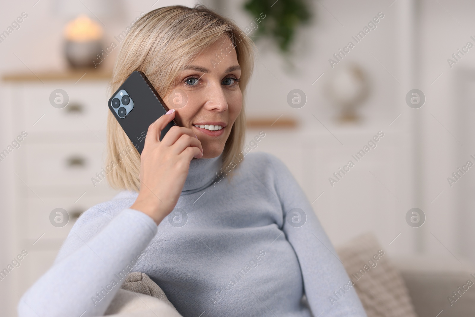 Photo of Happy woman talking on phone at home, space for text