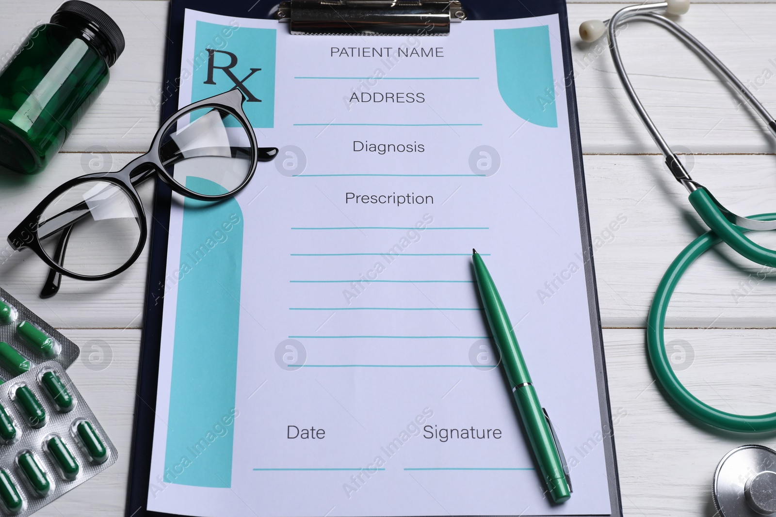 Photo of Clipboard with medical prescription form, stethoscope, pills and glasses on white wooden table