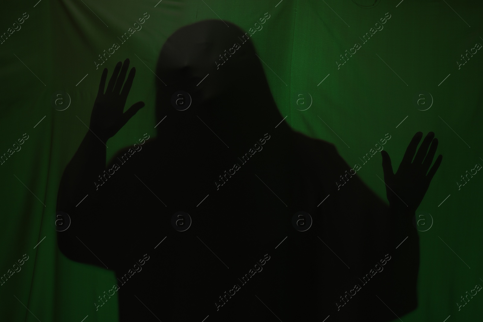 Photo of Silhouette of creepy ghost behind dark green cloth