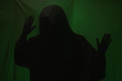 Photo of Silhouette of creepy ghost behind dark green cloth