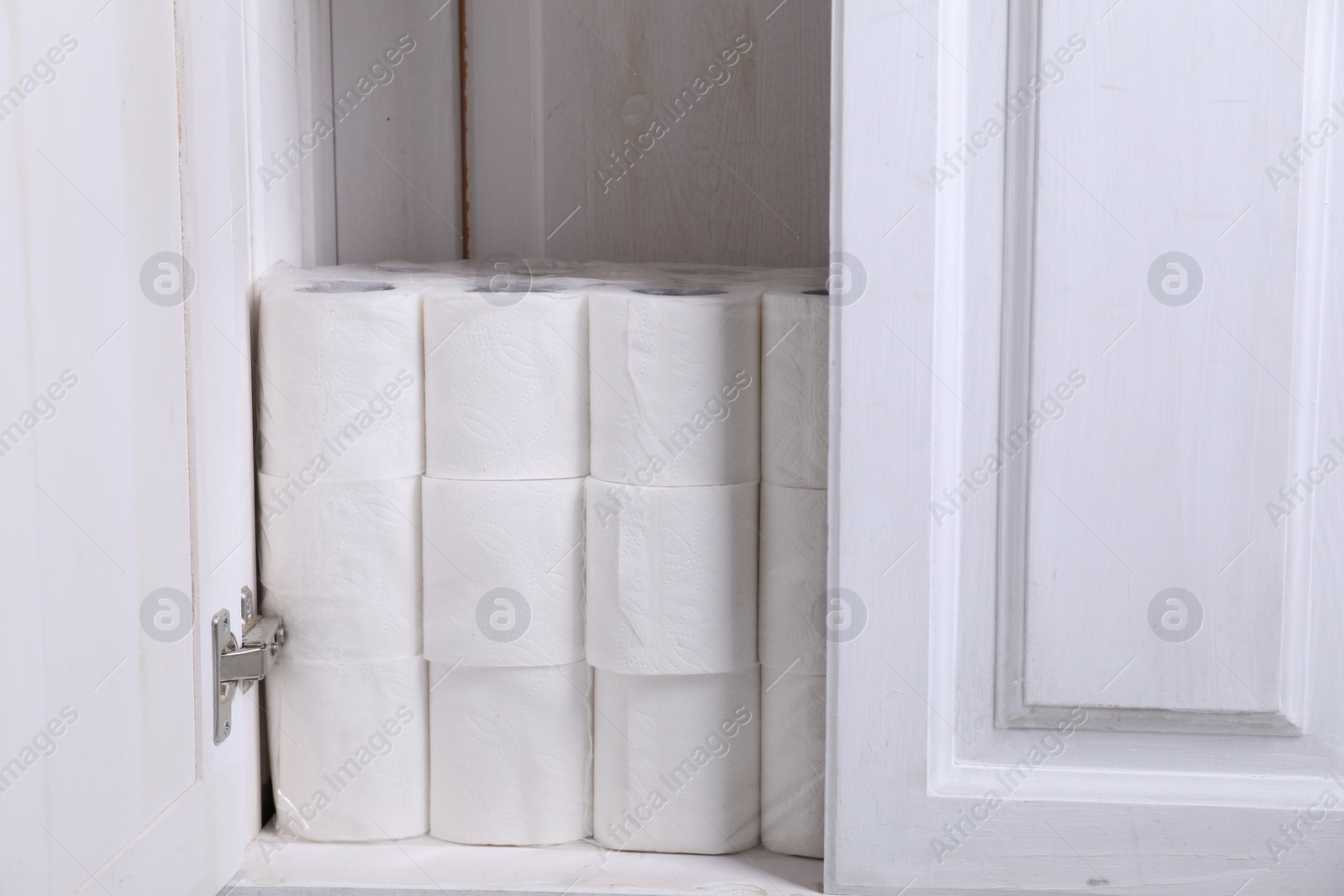 Photo of Stacked toilet paper rolls in cabinet indoors