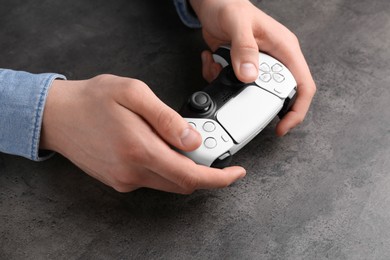 Man using wireless game controller at grey table, closeup