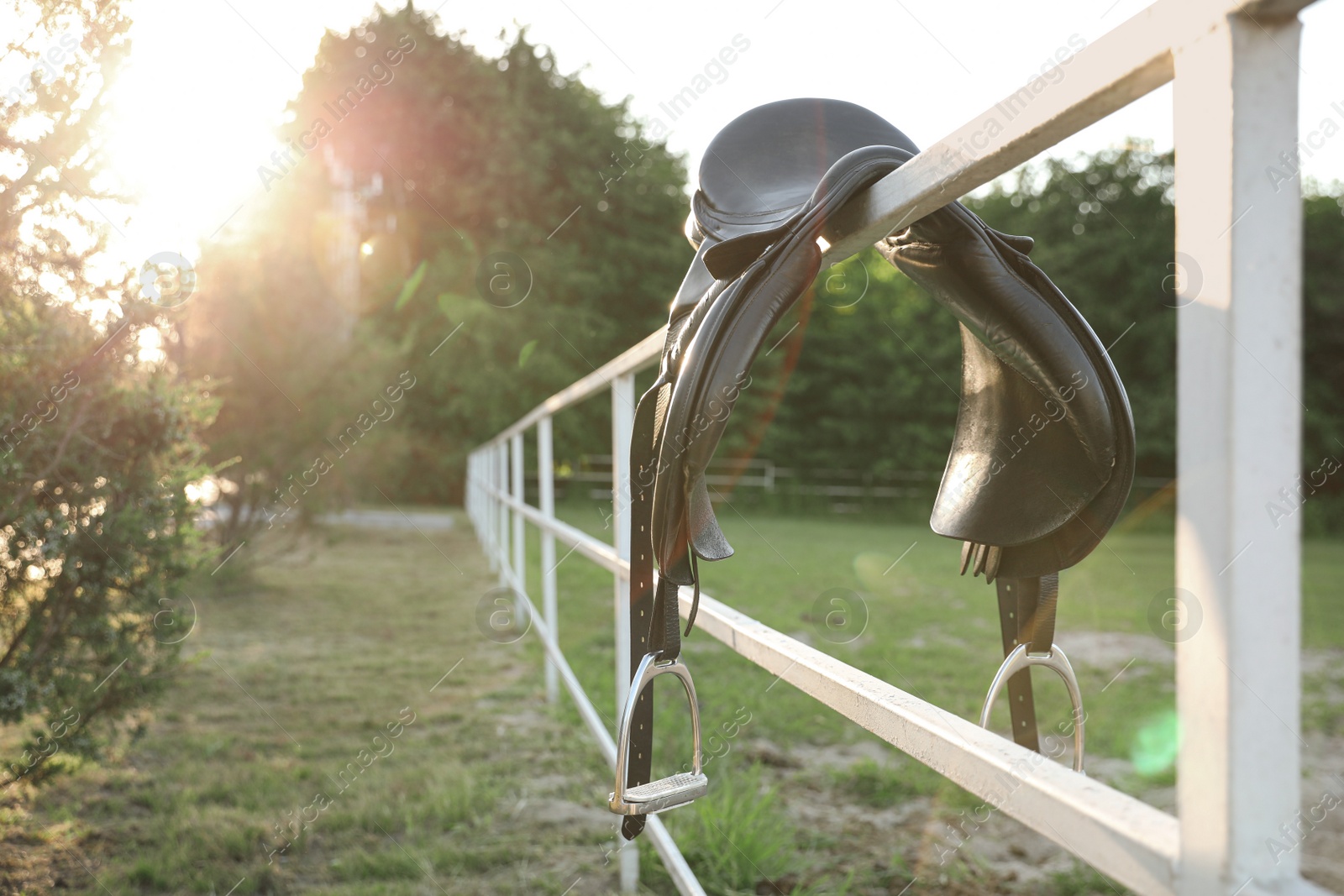 Photo of Leather horse saddle on wooden fence outdoors