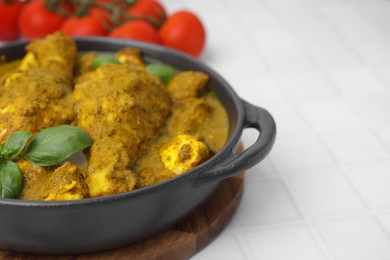 Photo of Delicious chicken with curry sauce and basil on white tiled table, closeup. Space for text