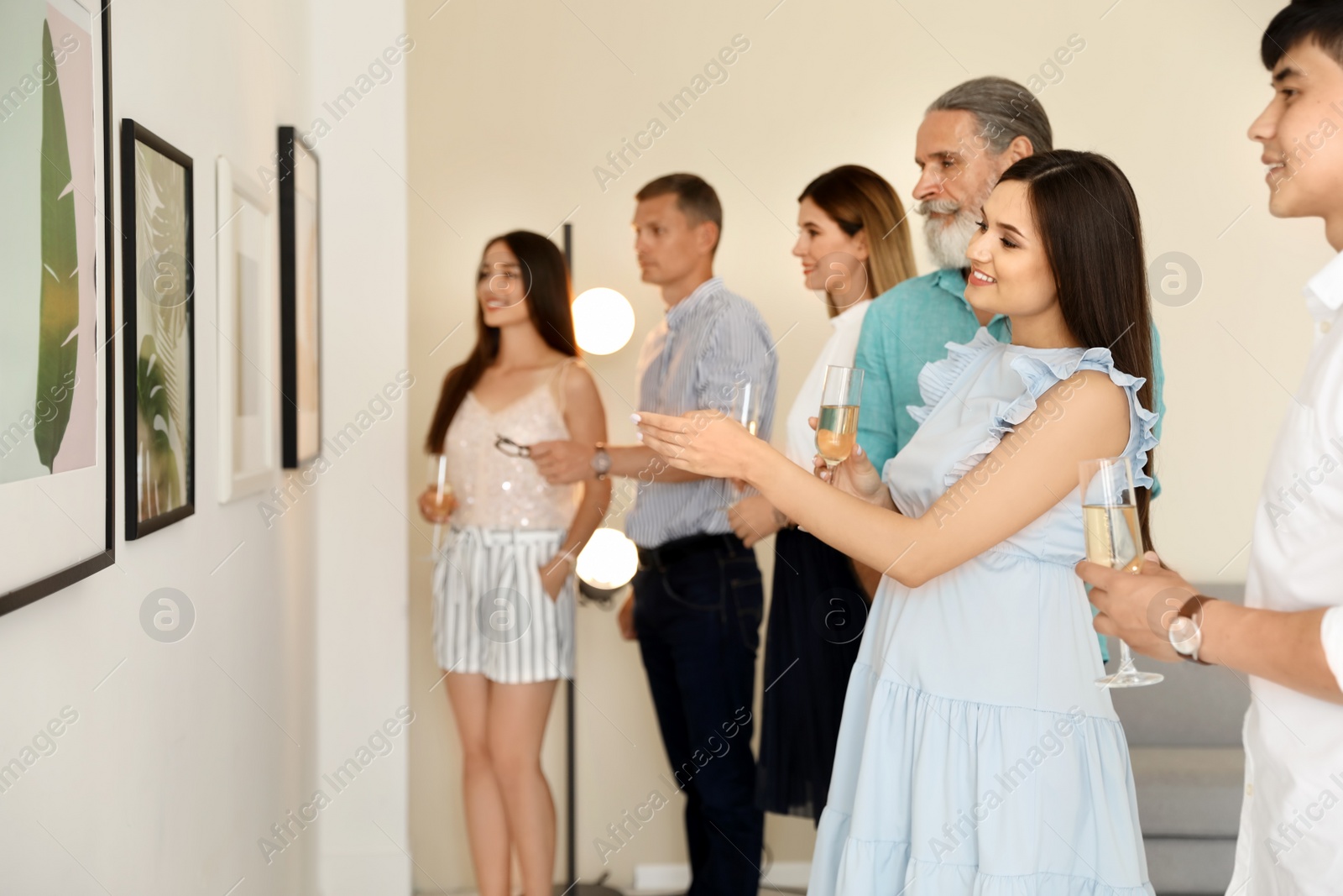 Photo of Group of people with glasses of champagne at exhibition in art gallery