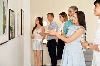 Photo of Group of people with glasses of champagne at exhibition in art gallery