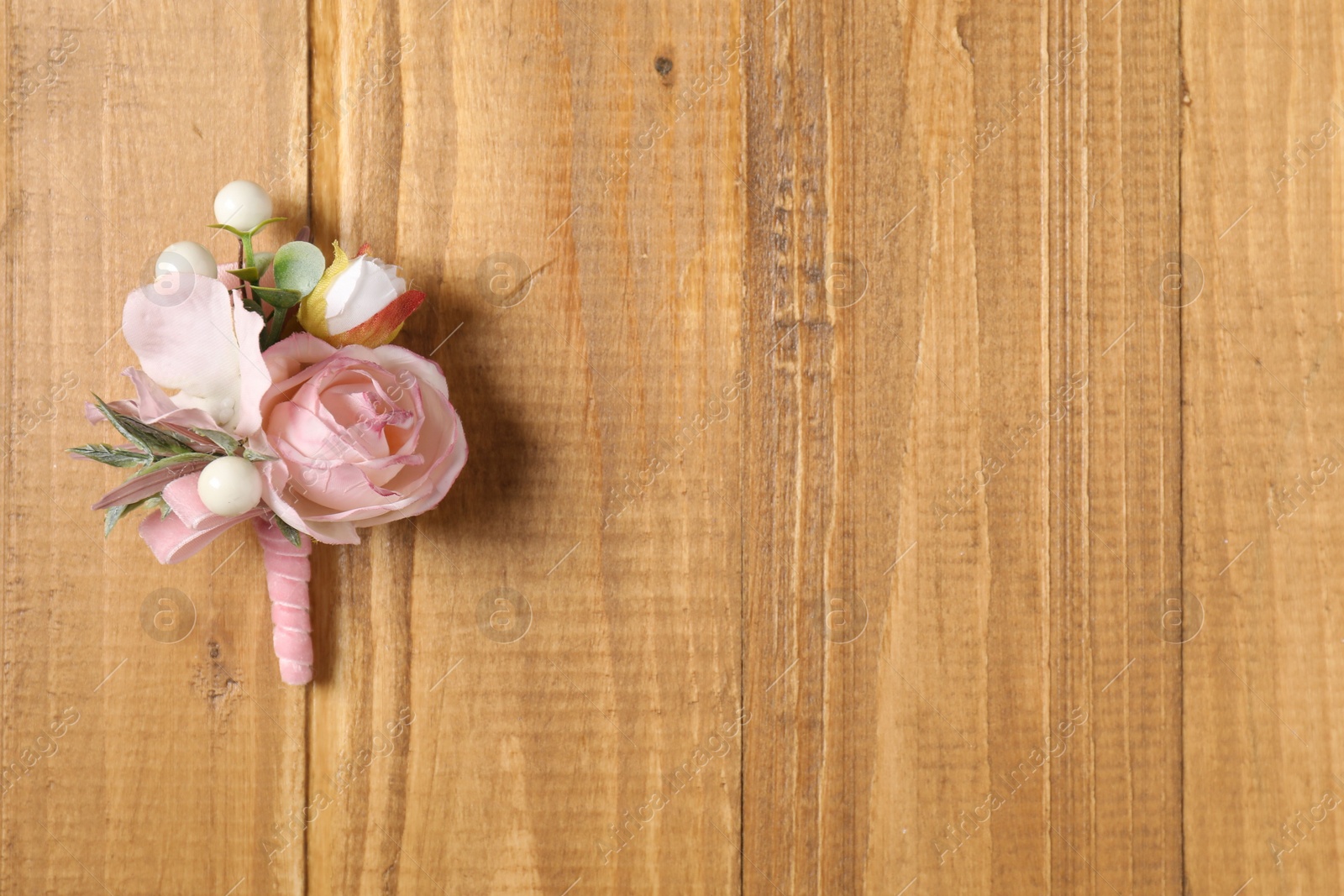 Photo of Stylish pink boutonniere on wooden table, top view. Space for text
