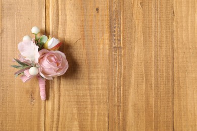 Photo of Stylish pink boutonniere on wooden table, top view. Space for text