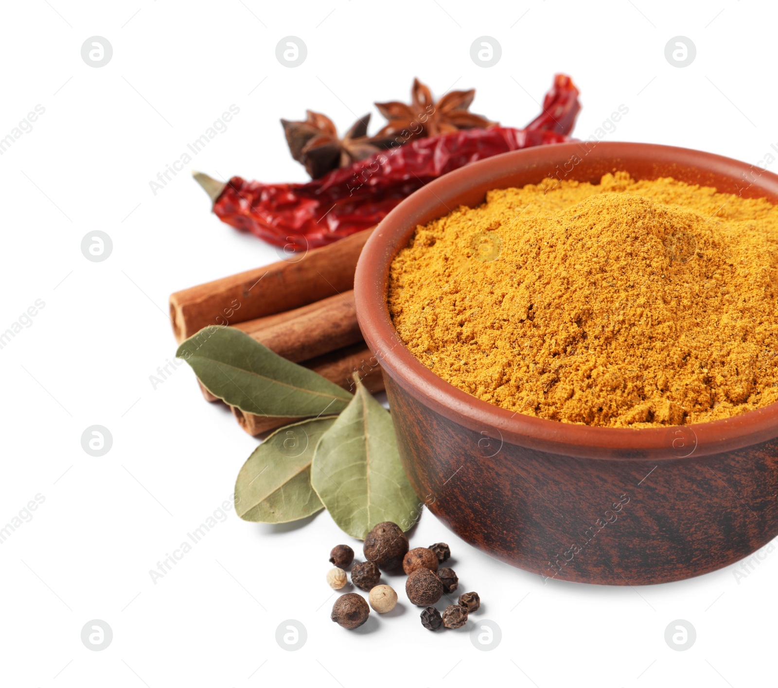 Photo of Curry powder in bowl and other spices isolated on white