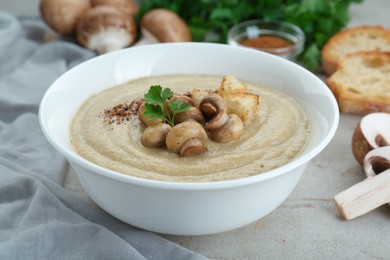 Photo of Delicious cream soup with mushrooms and croutons on beige textured table, closeup