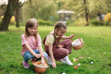 Easter celebration. Cute little girls hunting eggs outdoors