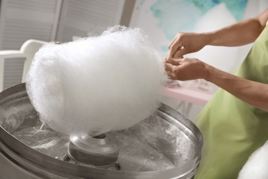 Photo of Woman making cotton candy using modern machine indoors, closeup