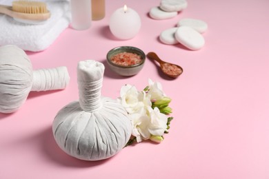 Photo of Herbal massage bags and other spa products on pink background, space for text