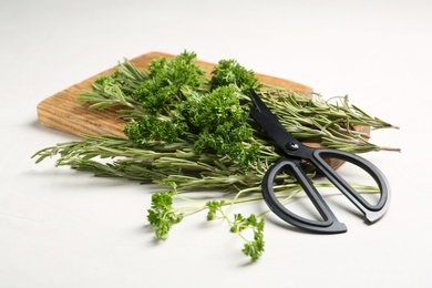 Rosemary, parsley and scissors on light table. Aromatic herbs