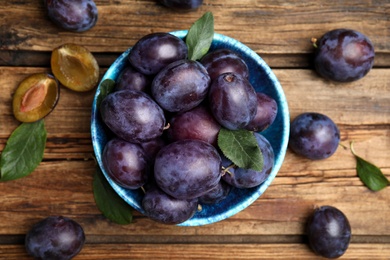 Photo of Delicious ripe plums on wooden table, flat lay