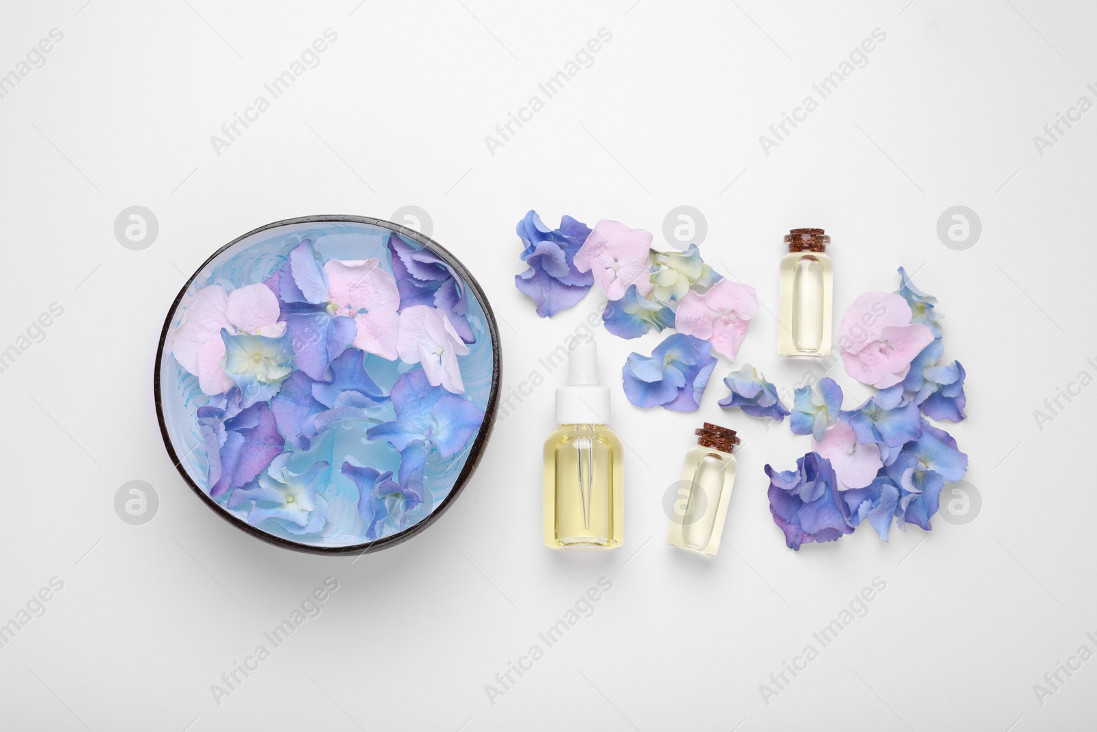 Photo of Spa composition. Aromatic water in bowl, flowers and bottles of essential oil on white background, flat lay