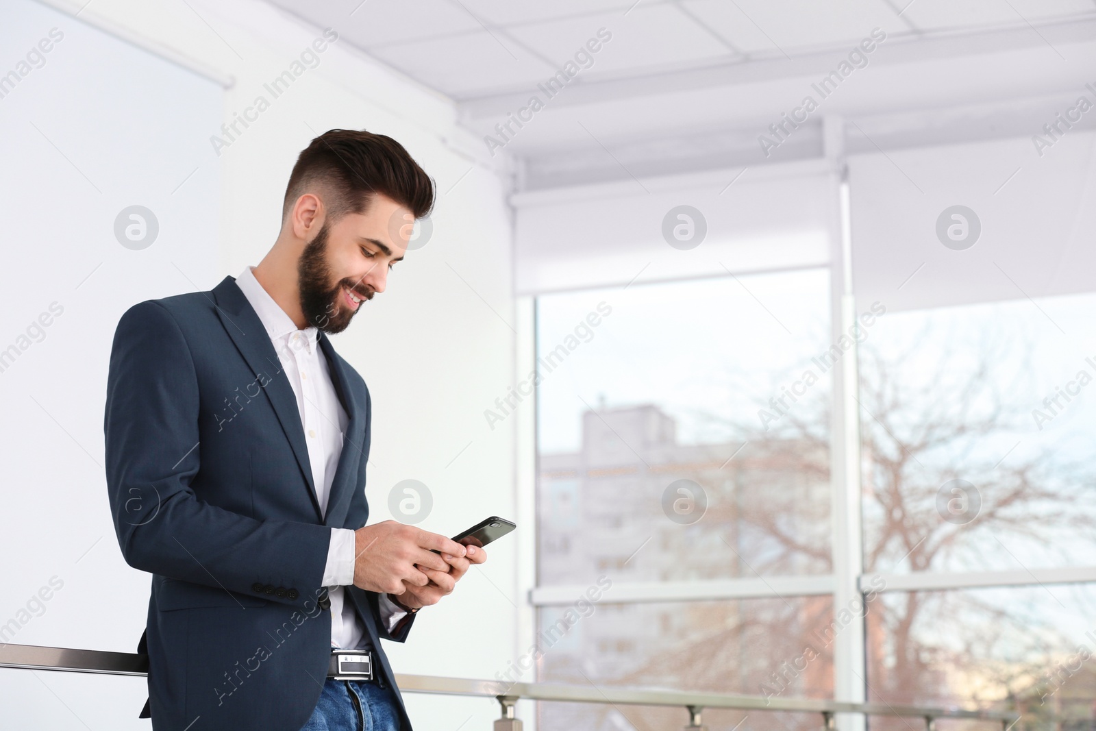 Photo of Handsome young man using phone in light room. Working time