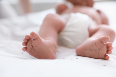 Photo of Newborn baby lying on bed, closeup of legs