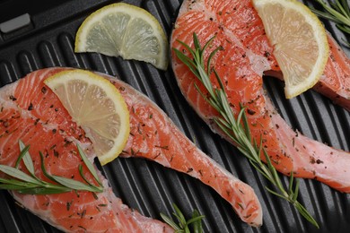Photo of Cooking salmon. Grill with fresh fish steaks, lemon and rosemary, top view