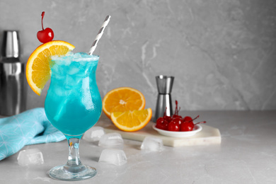 Photo of Tasty Blue Lagoon cocktail on light grey marble table. Space for text