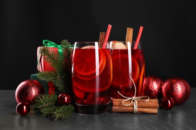 Photo of Delicious Sangria drink in glasses and Christmas decorations on dark textured table, closeup