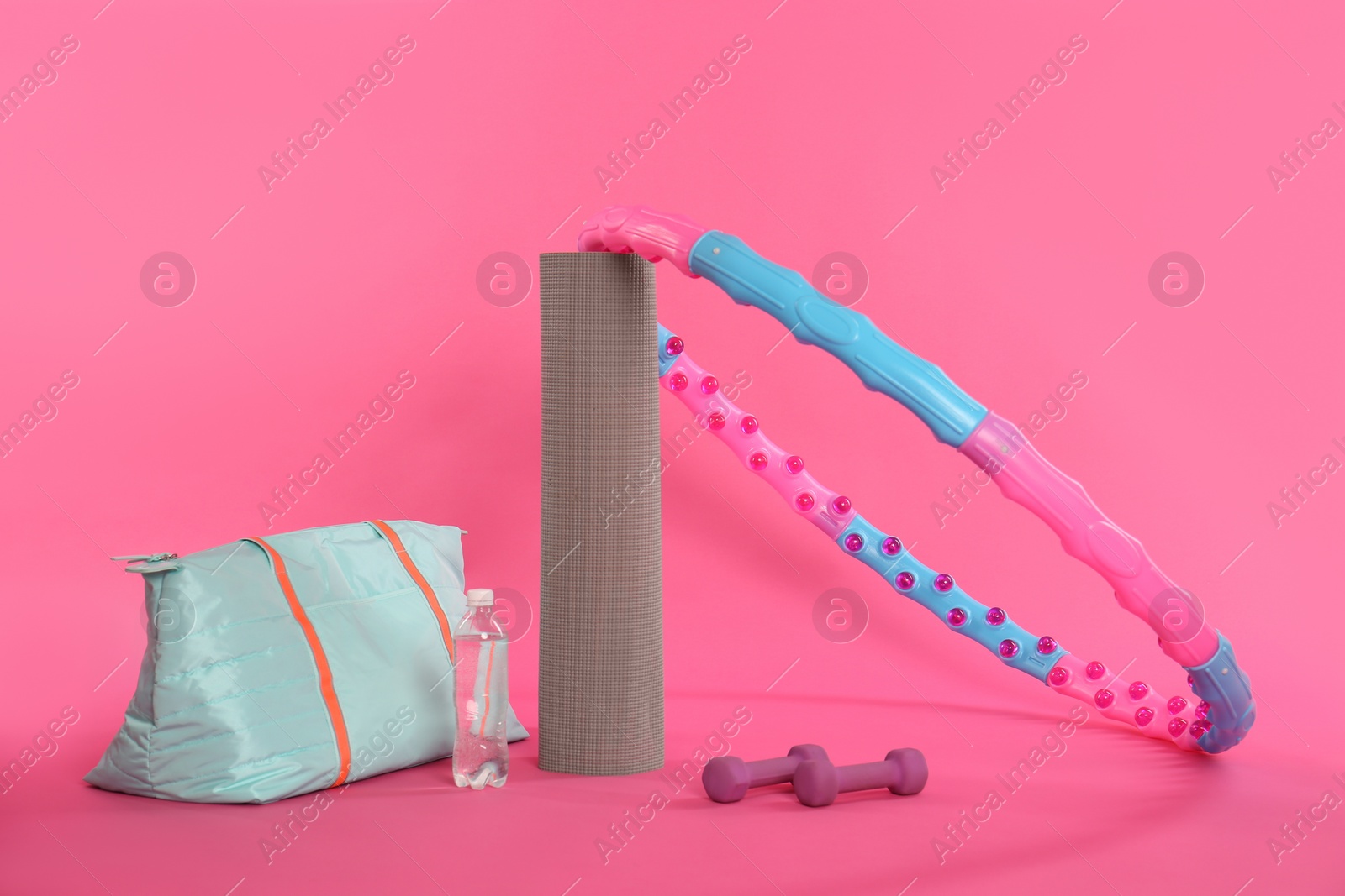 Photo of Hula hoop, gym bag, bottle of water, dumbbells and yoga mat on pink background