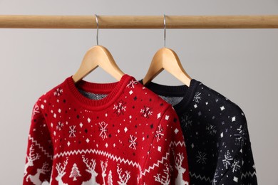 Photo of Rack with Christmas sweaters on light background