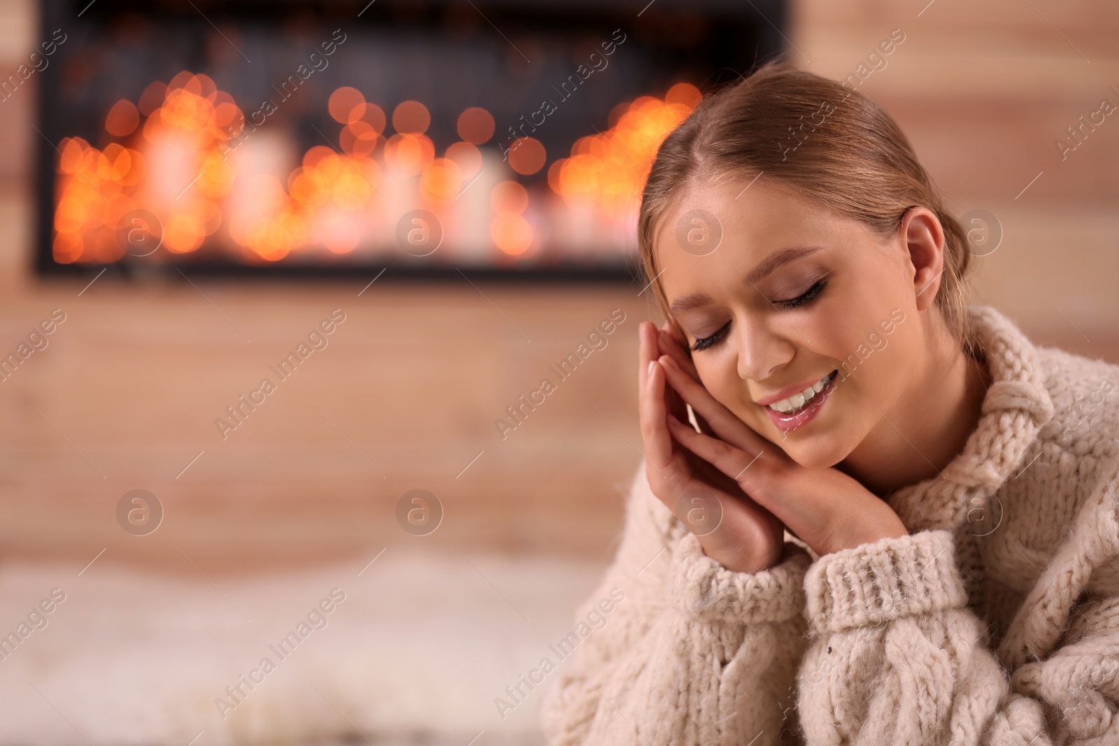 Photo of Beautiful young woman in warm sweater at home, space for text. Winter season