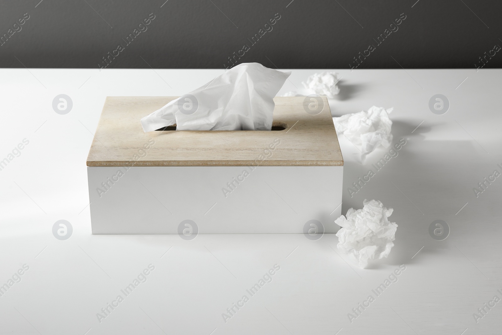 Photo of Used paper tissues and holder on white table