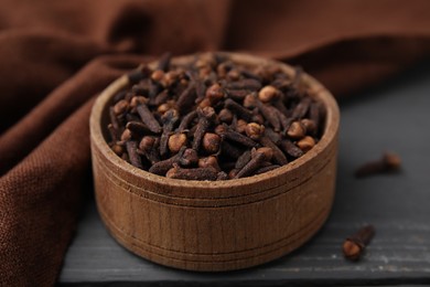 Photo of Aromatic cloves in bowl on grey wooden table, closeup