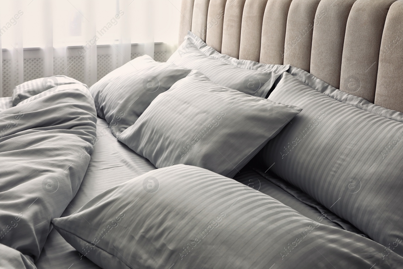 Photo of Comfortable bed with soft blanket and pillows indoors, closeup