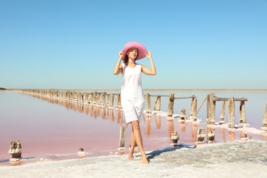 Photo of Beautiful woman with hat posing near pink lake on summer day