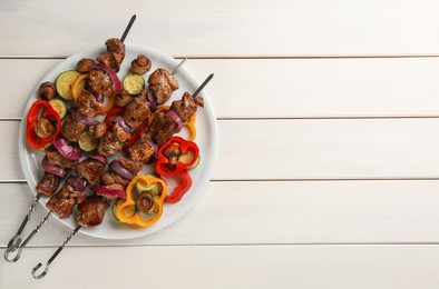 Metal skewers with delicious meat and vegetables served on white wooden table, top view. Space for text