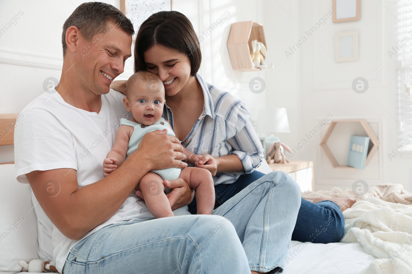 Photo of Happy family with their cute baby on bed at home