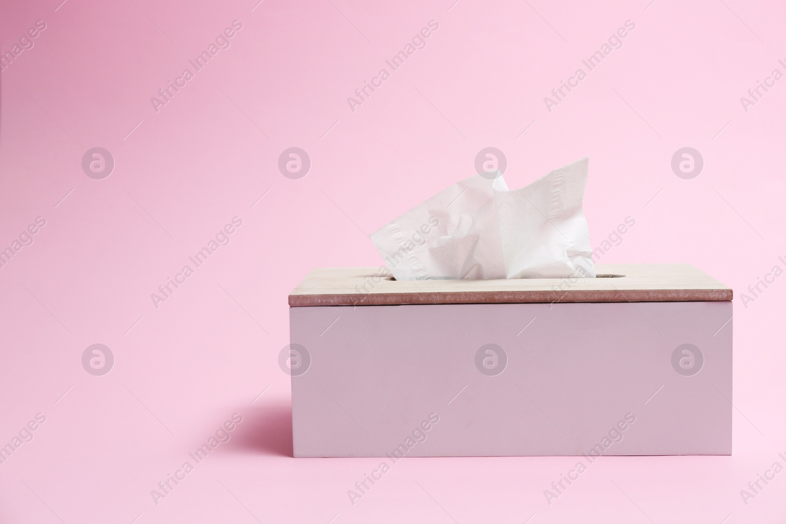 Photo of Holder with paper tissues on pink background