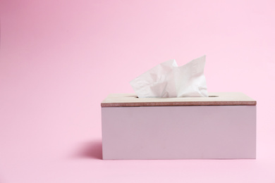 Photo of Holder with paper tissues on pink background