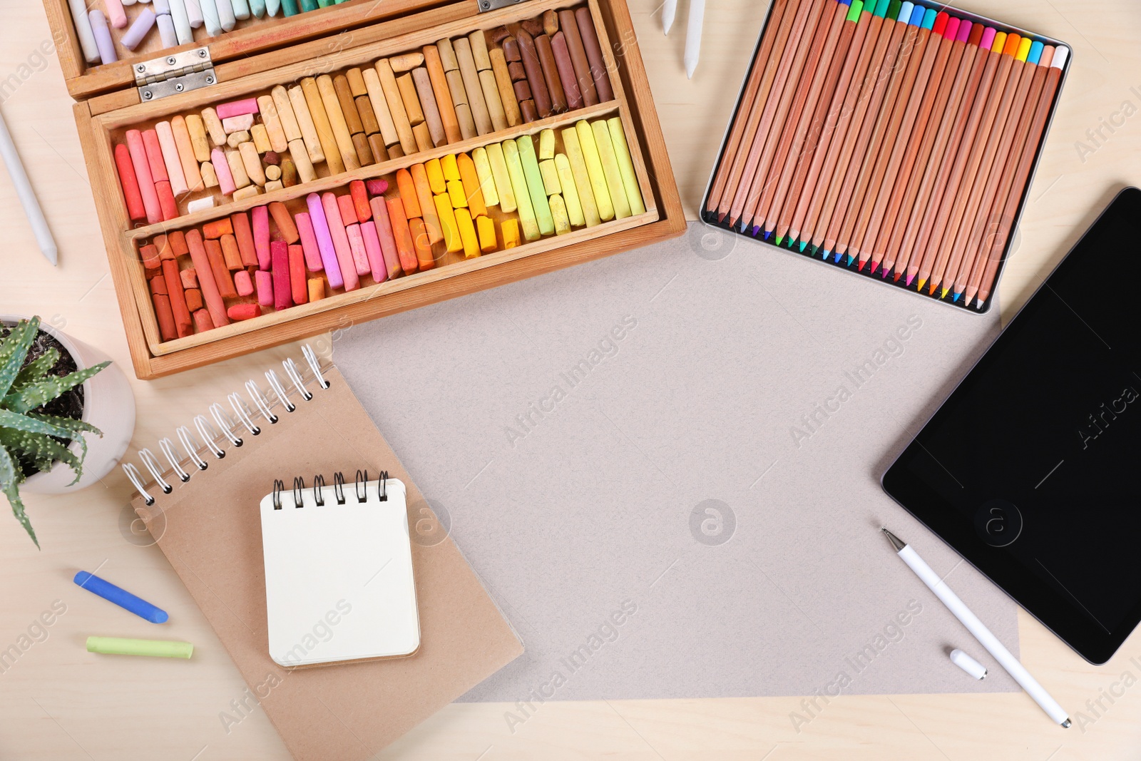 Photo of Layout with blank papers, soft pastels and other drawing supplies on wooden table at artist's workplace, top view. Space for design