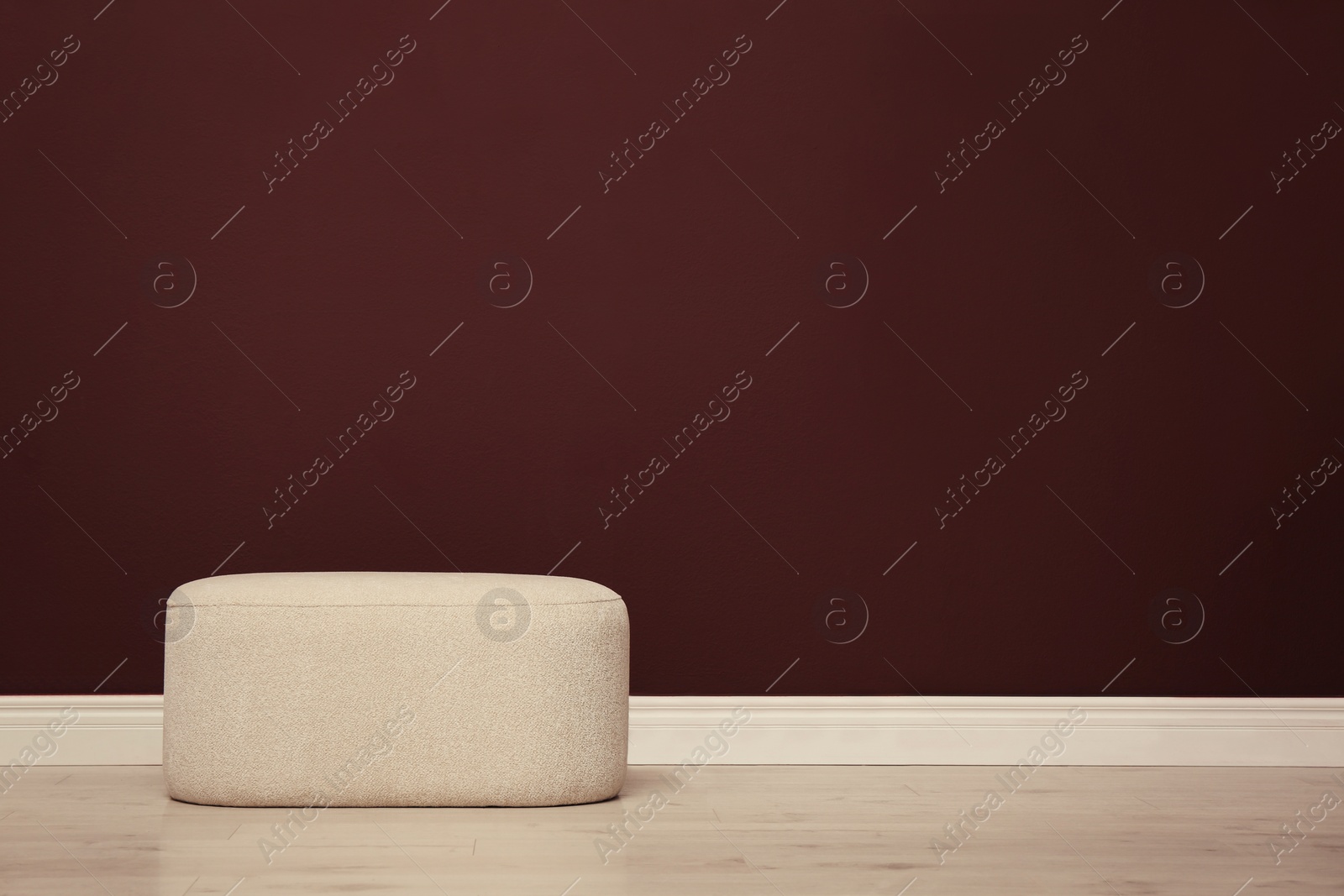 Photo of Stylish beige ottoman near brown wall indoors