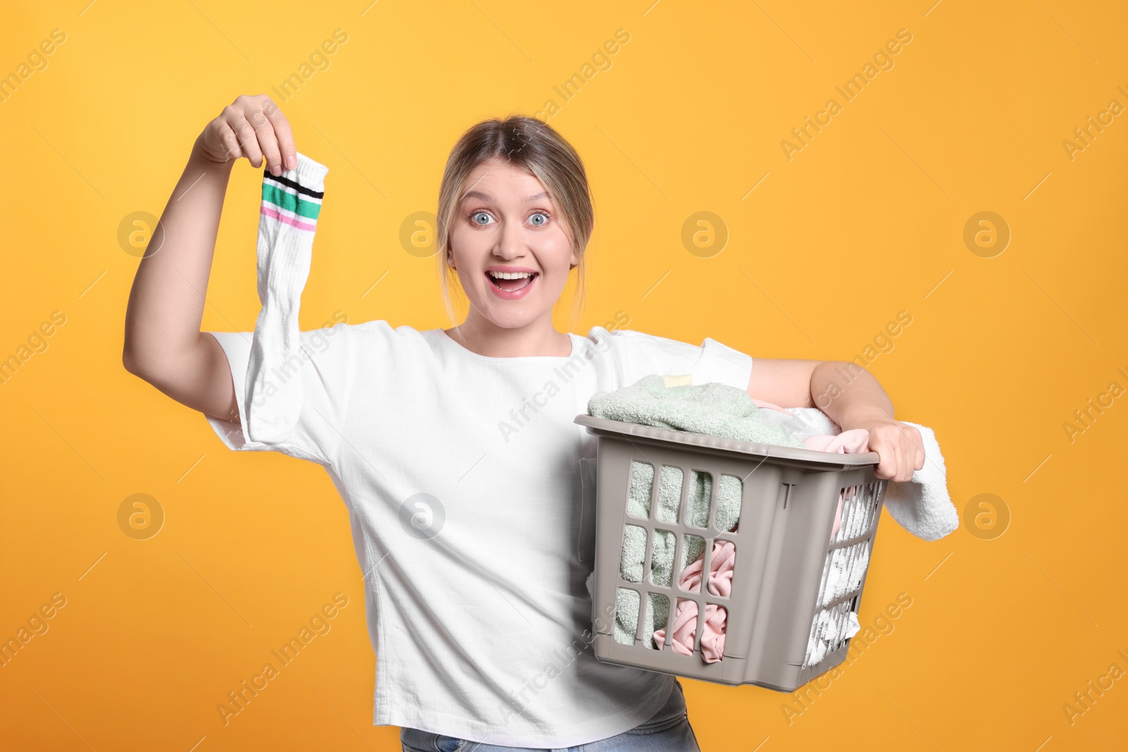 Photo of Emotional woman with basket full of laundry on orange background