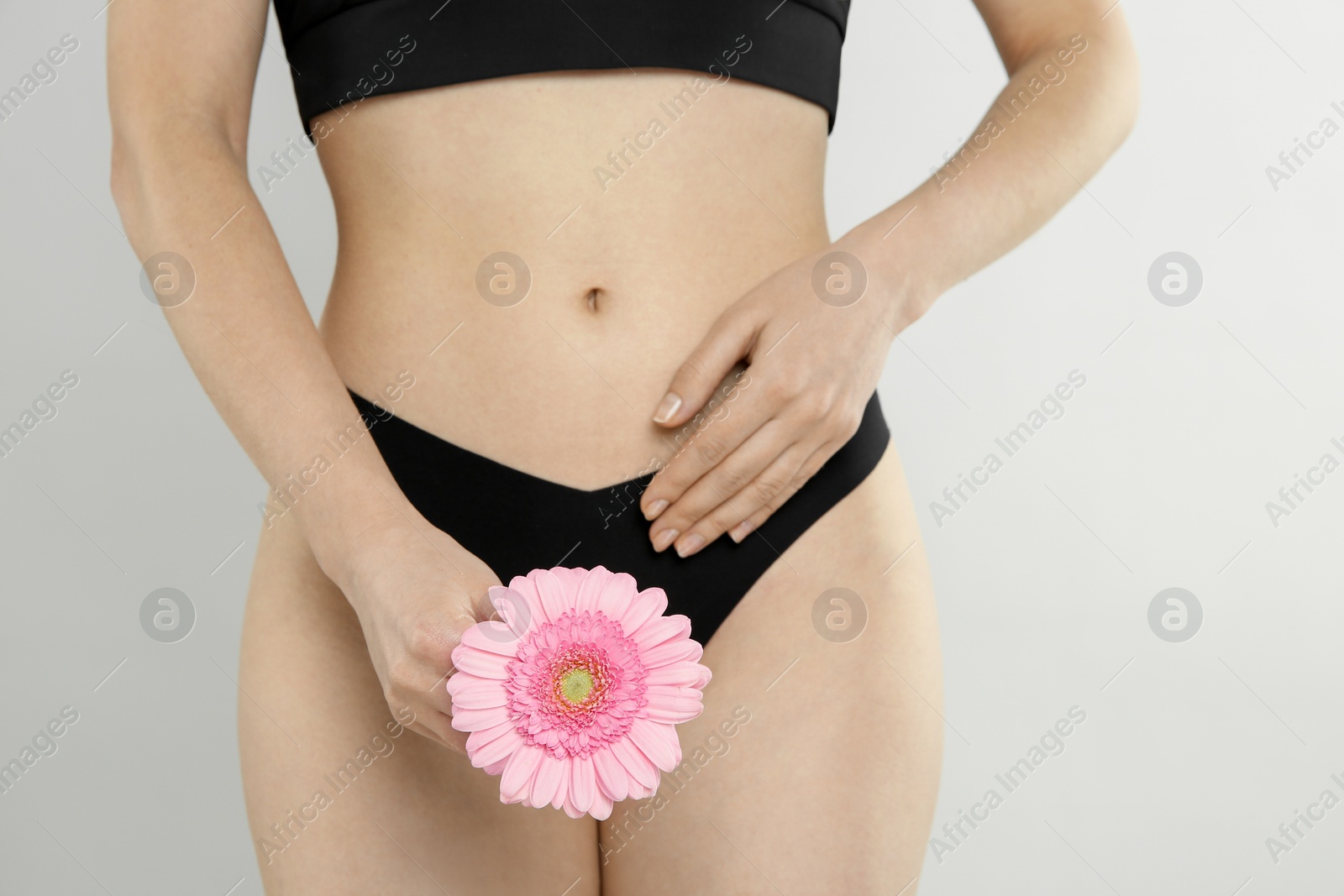 Photo of Gynecology. Woman in underwear with gerbera flower on light background, closeup